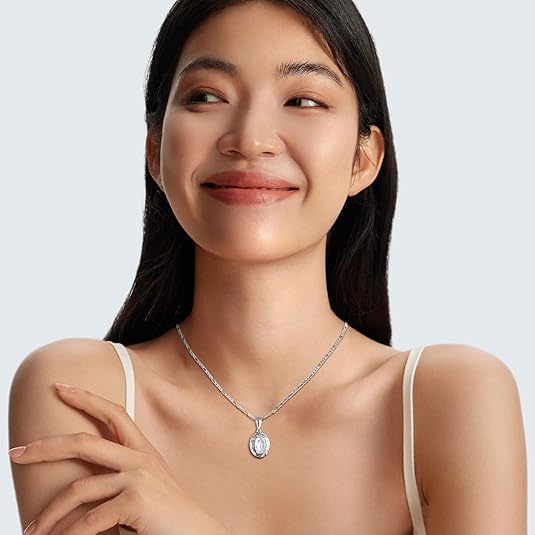 Woman wearing a silver necklace with a pendant on a plain background